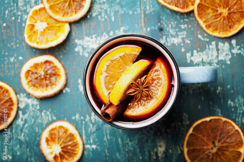 Warm christmas mulled wine or gluhwein with spices and orange slices on wooden teal table top view. Traditional drink on winter holiday.