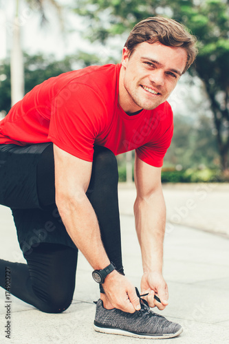 Smiling Sporty Man Tying Shoelaces Outdoors