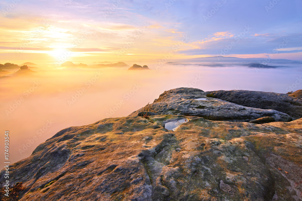 Fototapeta premium Strong sun rays make long strips in the mist. Autumn sunny view over misty valley