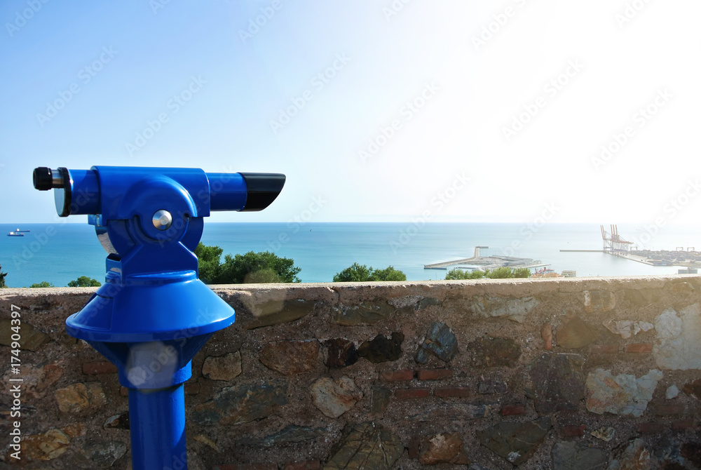 View point at Malaga fortress (Alcazaba), a blue coin telescope and a beautiful view to Mediterranean sea and a city port, Andalusia, Spain.
