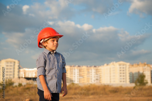 cute kid wearing builder helmet on the new buildings background © ruslanshug
