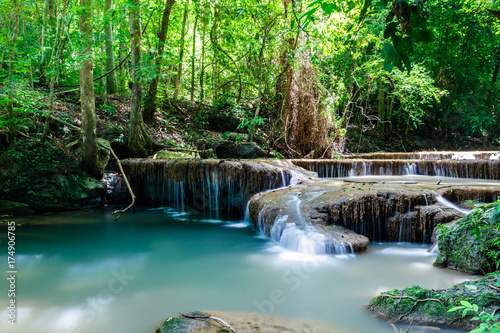 Tranquil waterfall and pool shaded by tropical jungle plants in Erawan National Park, western Thailand.