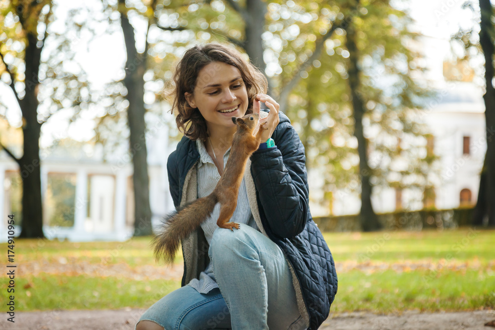 Beautiful young woman feeding a squirrel in an autumn park, a squirrel sitting on a girl Beautiful young woman feeding a squirrel in an autumn park, a squirrel sitting on a girl