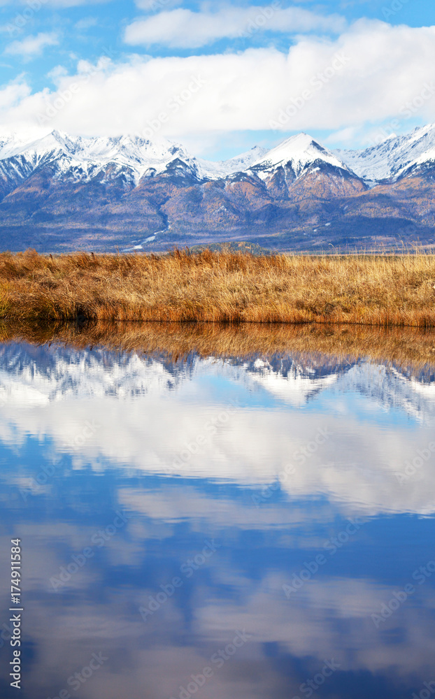 Beautiful autumn landscape with reflection of snow-capped mountains in lake water