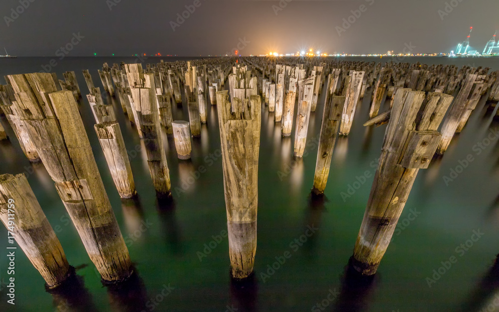 Wooden Princes Pier at night in Melbourne Australia with green water and myst in the background.