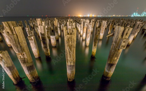 Wooden Princes Pier at night in Melbourne Australia with green water and myst in the background.