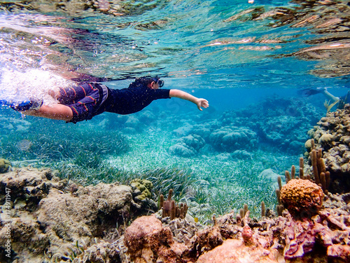 Underwater image of boy snorkeling through coral reef near Ambergris Caye, Belize photo