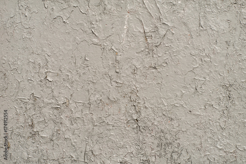 White-gray surface of a wall with cracked paint, plaster, close-up 