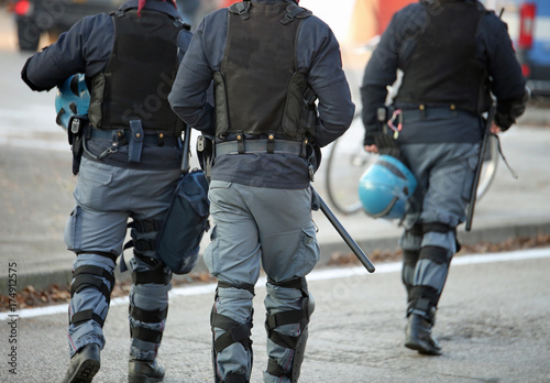 three policemen with anti-bulletproof jacket in anti-riot unifor