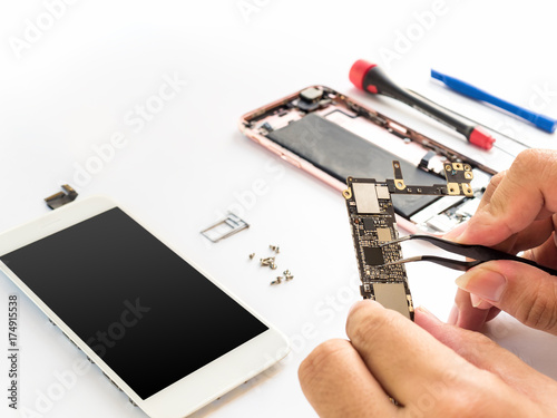 Close-up of technician hand clamping processor on smartphone logic board on smartphone component background with copy space photo