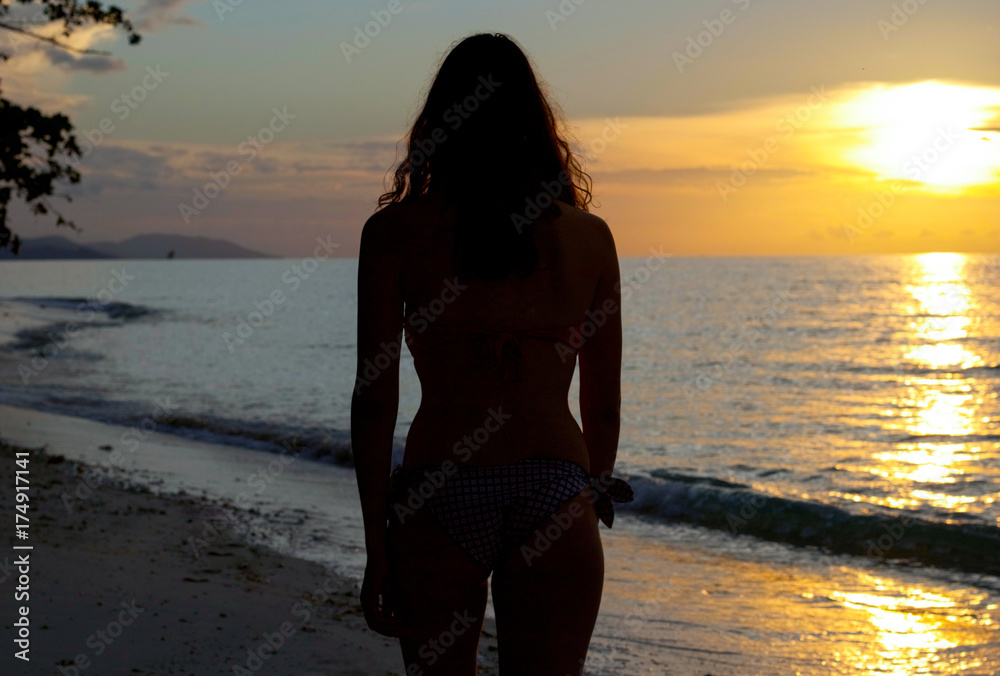 silhouette of young woman back at sunset by the beach