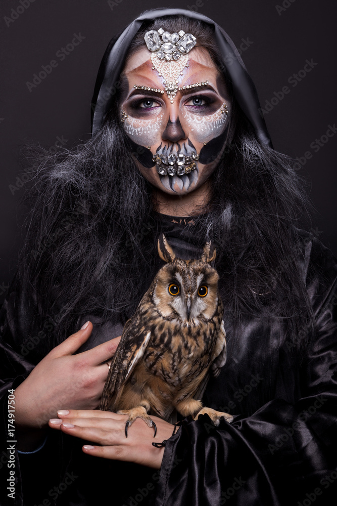 girl with a make-up for halloween with an owl in hands