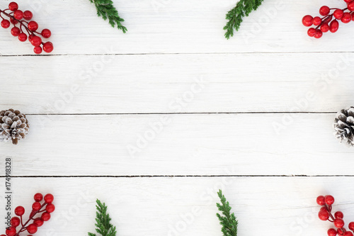 Christmas background. Christmas frame made of fir leaves, pine cones and holly berry decoration rustic elements on white wooden. Creative flat lay, top view design