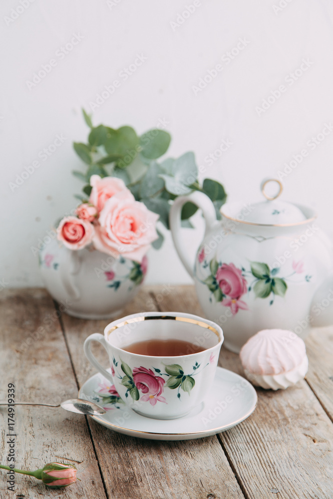 tea set in composition with flowers and marshmallows. Coffee mug on a saucer, a teapot and a sugar bowl. Filmed in the interior