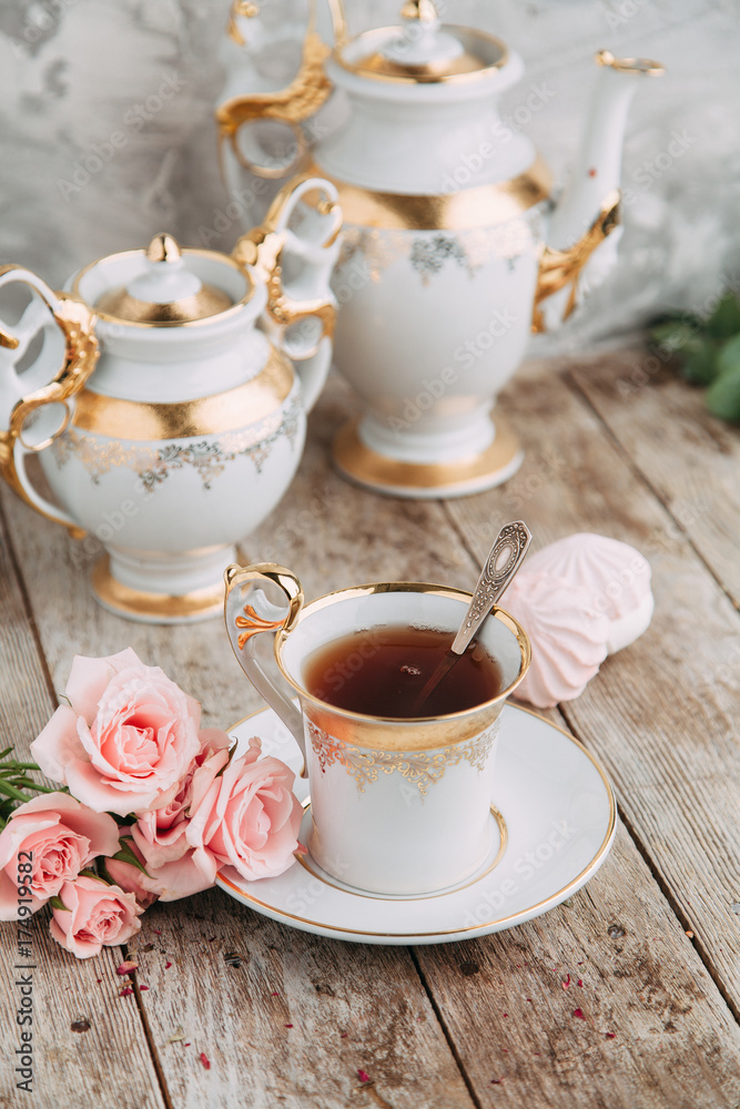 tea set in composition with flowers and marshmallows. Coffee mug on a saucer, a teapot and a sugar bowl. Filmed in the interior tea set in composition with flowers and marshmallows. Coffee mug on a saucer, a teapot and a sugar bowl. Filmed in the interior