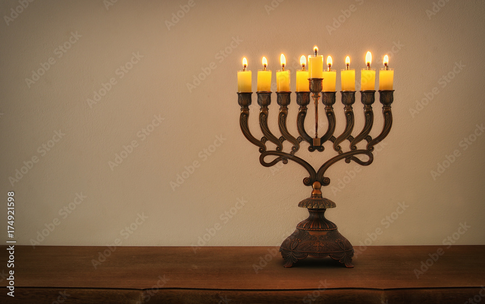 Low key image of jewish holiday Hanukkah background with menorah (traditional candelabra) and burning candles Low key image of jewish holiday Hanukkah background with menorah (traditional candelabra) and burning candles
