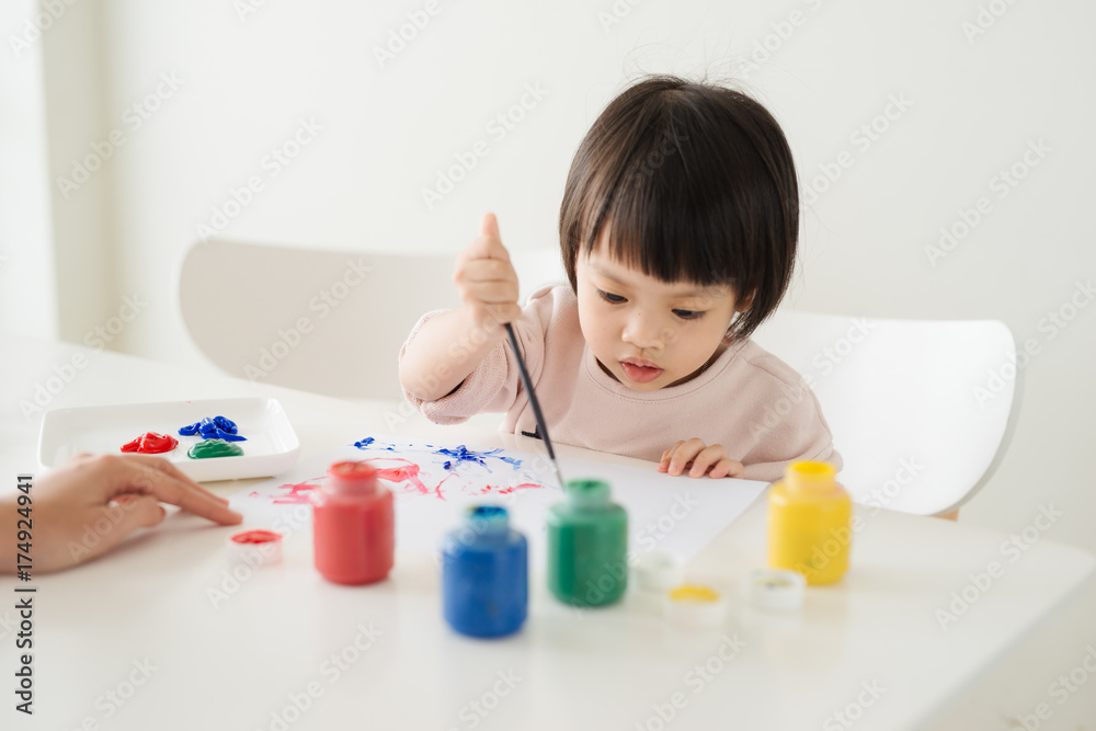 Little asian girl painting with paintbrush and colorful paints Little asian girl painting with paintbrush and colorful paints