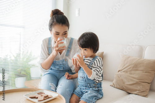 фотографія Happy family of asian mom is drinking milk with her cute daughter in the morning