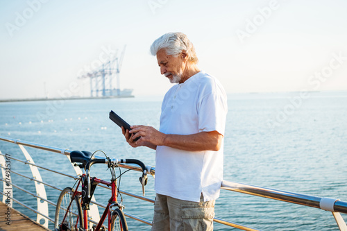 Portrait of retirement handsome senior man using tablet computer on seafront