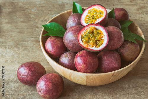 Passion fruit on wood bowl put on wood table in vintage tone style for background or wallpaper. Ripe passion fruit so sweet and sour suitable make dessert for summer. Passion fruit is tropical fruit.