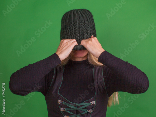 A woman covers her face with a knitted hat. Isolation photo