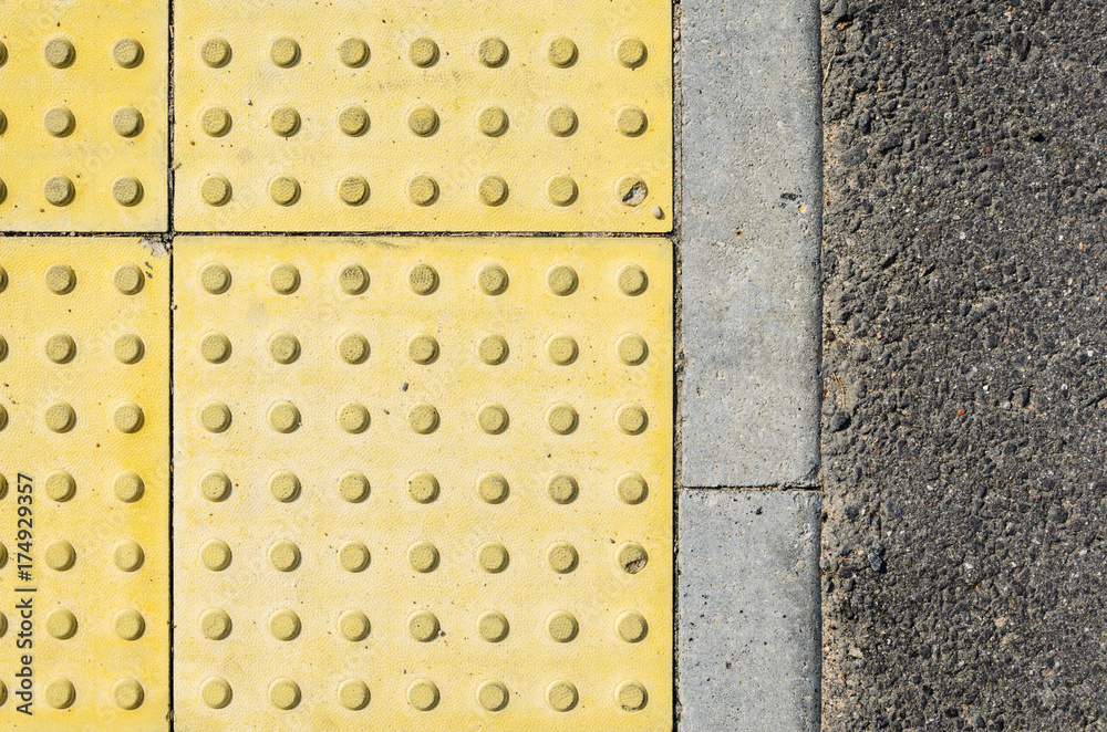 Fototapeta premium Adjoining Pavement with a Tactile Tile for Blind Peoples and an Asphalt Road. Joint of Road Surfaces Texture