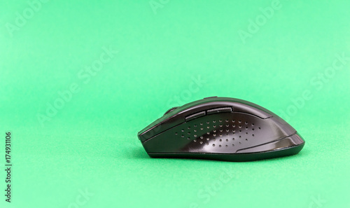 Black computer mouse on the green background.
