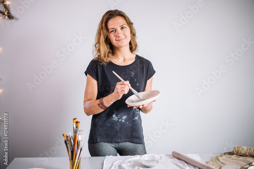 potter woman paints ceramic cup. Woman working In her pottery studio photo