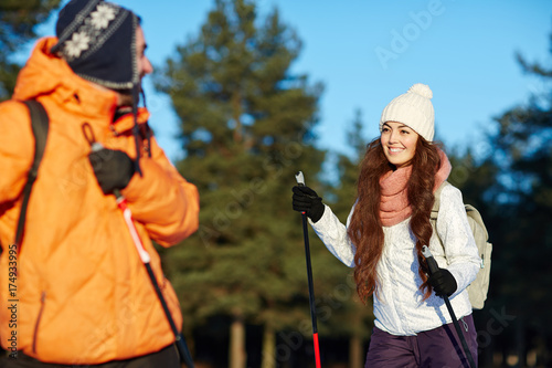 Young woman in winterwear talking to her husband during ski trip in forest
