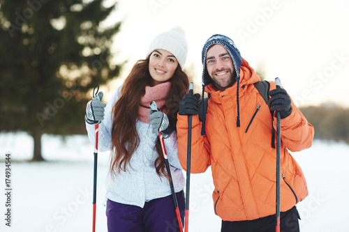 Young sweethearts skiing in forest together on winter weekend