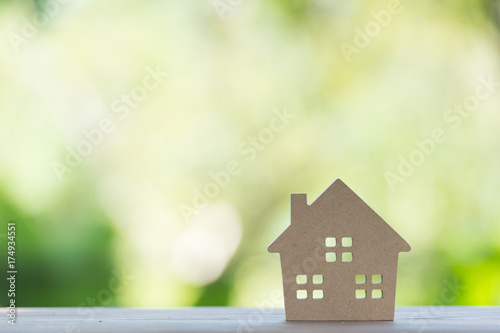 miniature house on wooden mock up over blurred green garden on day noon light.Image for property real estate investment concept.