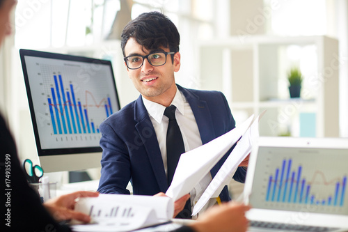 Successful financier showing some papers to co-worker during discussion
