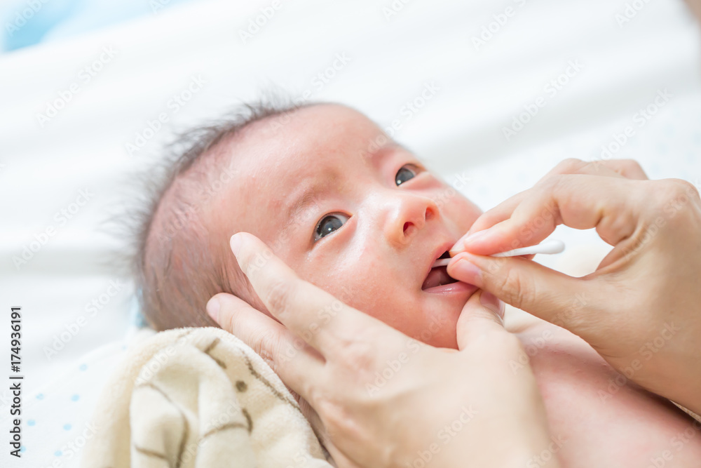 Asian newborn baby cleaning tongue, cheek bulge and mouth after bath