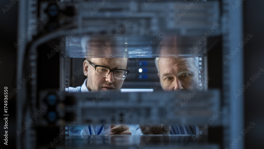 Two Server Engineers Install Hardware in Server Rack. They Work in Big Modern Data Center. Two Server Engineers Install Hardware in Server Rack. They Work in Big Modern Data Center.