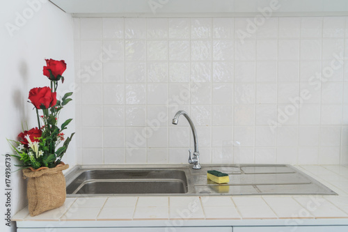 sink with sponge in a kitchen and red rose