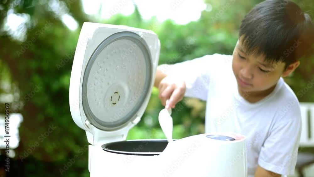Preteen asian Thai boy and electric rice cooker that cooking a very ...