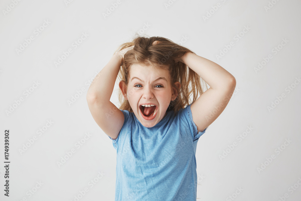 Beautiful little girl with light hair screaming loudly, holding hair with hands, being scared with big spider on the wall in bedroom. Beautiful little girl with light hair screaming loudly, holding hair with hands, being scared with big spider on the wall in bedroom.
