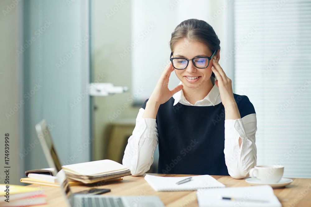 Young woman sitting by desk and reading paper or preparing business report Young woman sitting by desk and reading paper or preparing business report