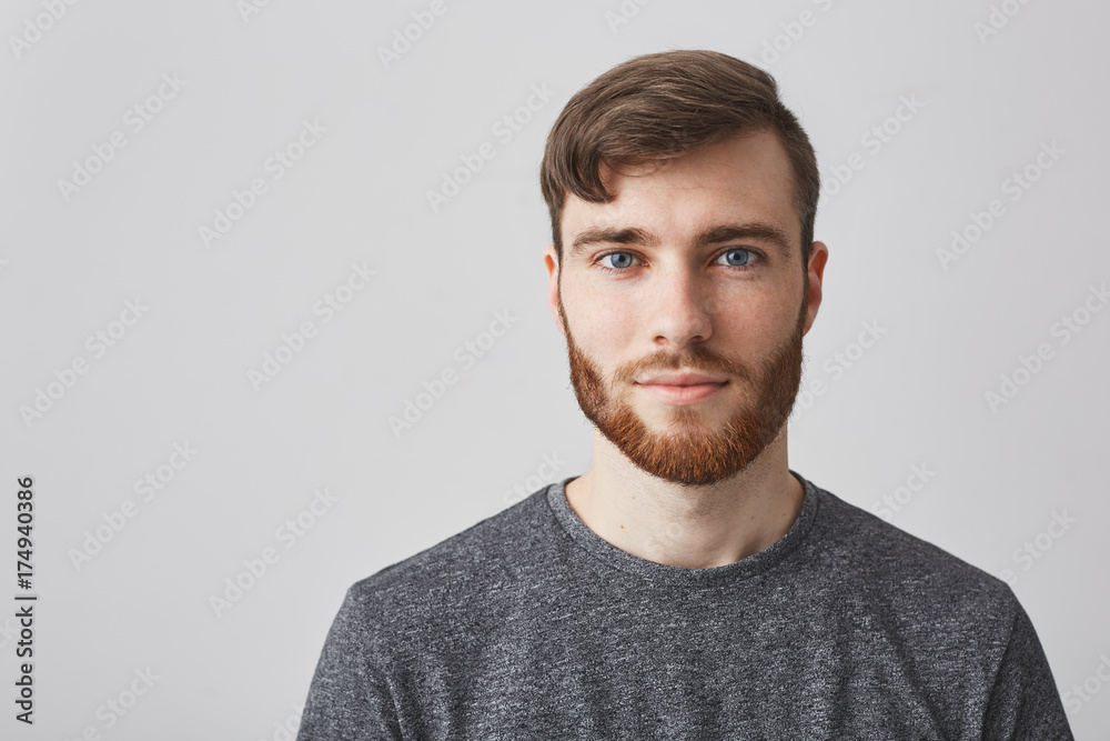 Close up portrait of beautiful manly bearded guy with stylish hairstyle smiling, looking in camera with happy and calm face expression. Close up portrait of beautiful manly bearded guy with stylish hairstyle smiling, looking in camera with happy and calm face expression.
