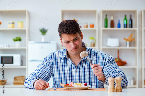 фотографія Man eating tasteless food at home for lunch