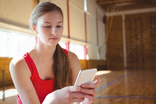 Close up of young woman using mobile phone in basketball court