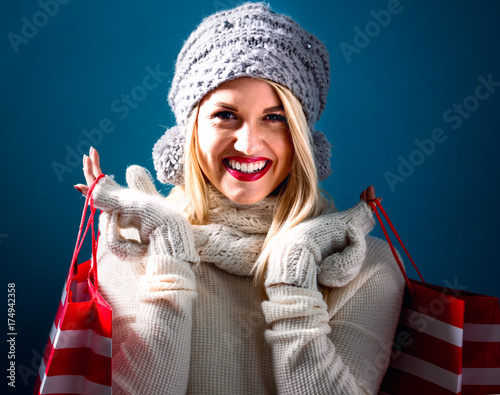 Happy young woman holding shopping bags on a blue background
