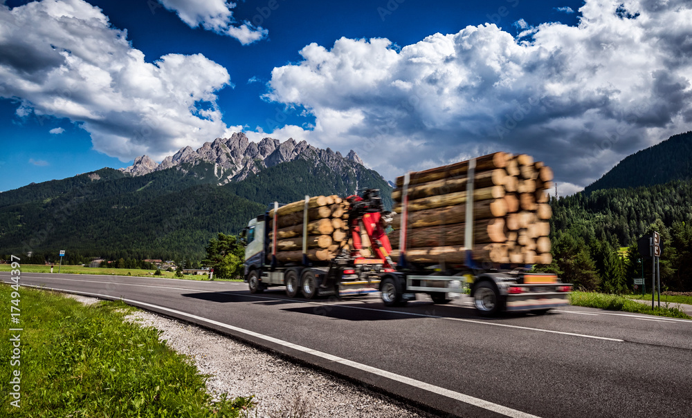 Timber truck rushes down the highway in the background the Alps. Truck Car in motion blur.