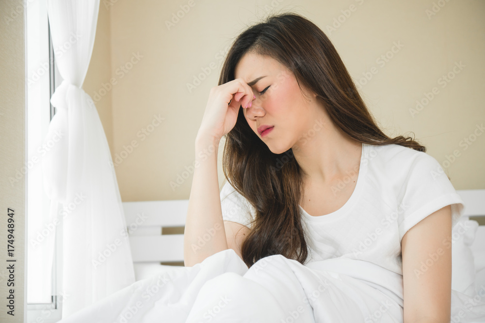 Asian woman have a headache in bedroom morning because sleep problem Asian woman have a headache in bedroom morning because sleep problem