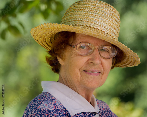 Portrait of a woman aged in glasses and a straw hat
