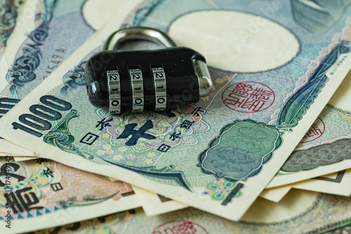 selective focus on combination lockpad on pile of japanese yen banknotes as financial safe haven or security concept photo