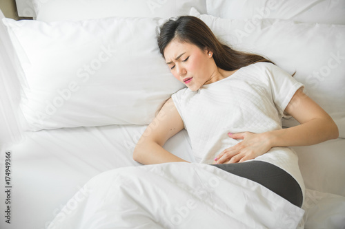 Asian woman have a stomachache in bedroom because menstruation