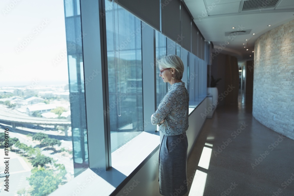 Thoughtful businesswoman standing by window Thoughtful businesswoman standing by window