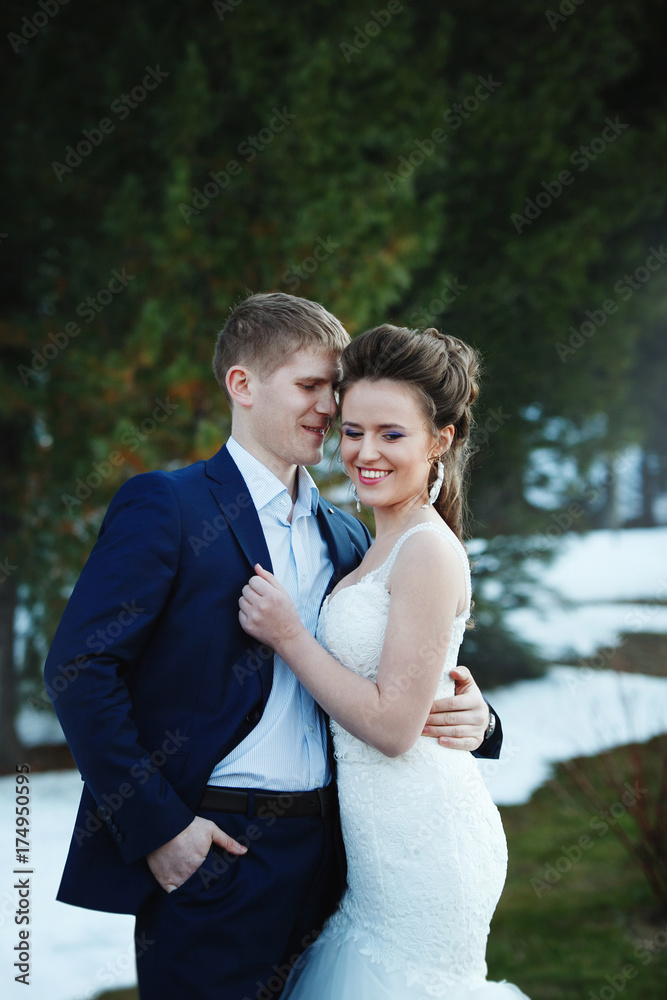 Winter wedding outdoors on snow background. Bride and groom are standing and hugging.