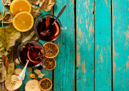 Hot mulled wine with orange, cinnamon, cardamom and anise on green wooden background. Top view